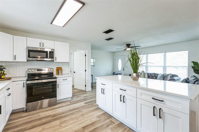 kitchen featuring appliances with stainless steel finishes, white cabinets, and light countertops