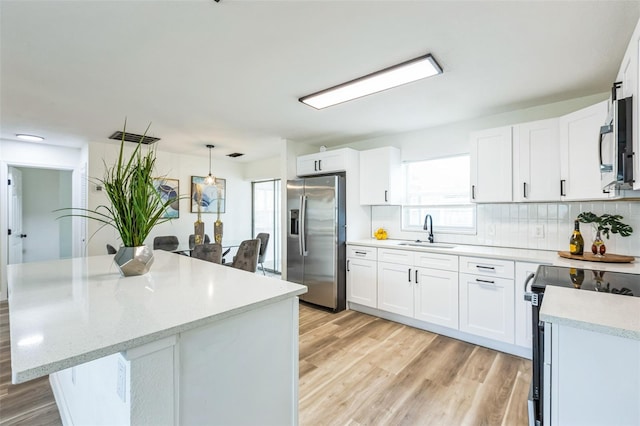 kitchen featuring white cabinetry, pendant lighting, stainless steel appliances, and a sink