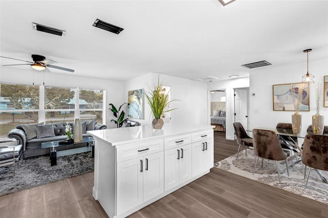 kitchen with light countertops, hanging light fixtures, dark wood-type flooring, open floor plan, and white cabinets