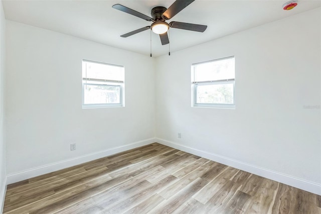 spare room featuring a healthy amount of sunlight, light wood-style flooring, baseboards, and ceiling fan