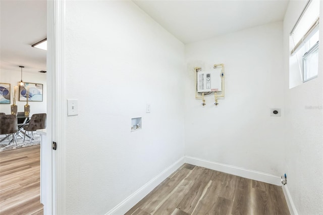 laundry area with laundry area, baseboards, electric dryer hookup, and wood finished floors