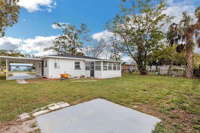 rear view of property with a yard, a carport, and a sunroom