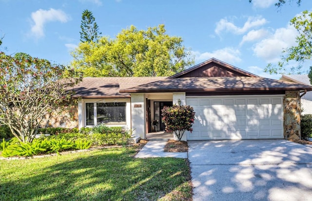 ranch-style home featuring a front lawn, concrete driveway, roof with shingles, a garage, and stone siding