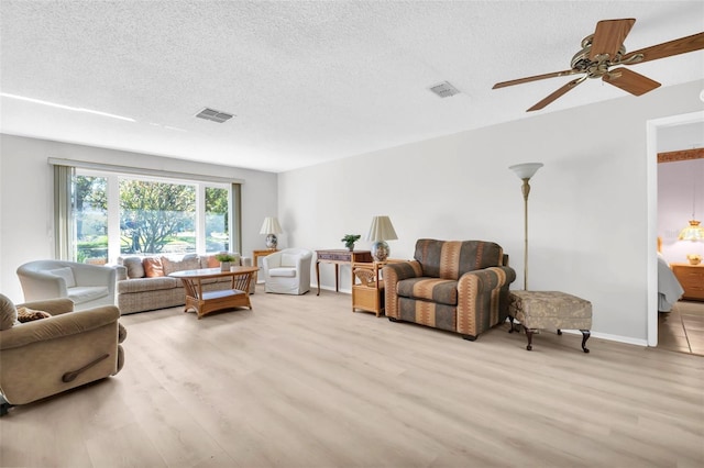 living room featuring visible vents, a textured ceiling, and wood finished floors