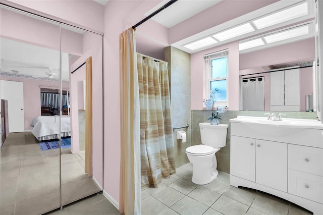 bathroom with vanity, tile patterned flooring, ensuite bathroom, tile walls, and toilet