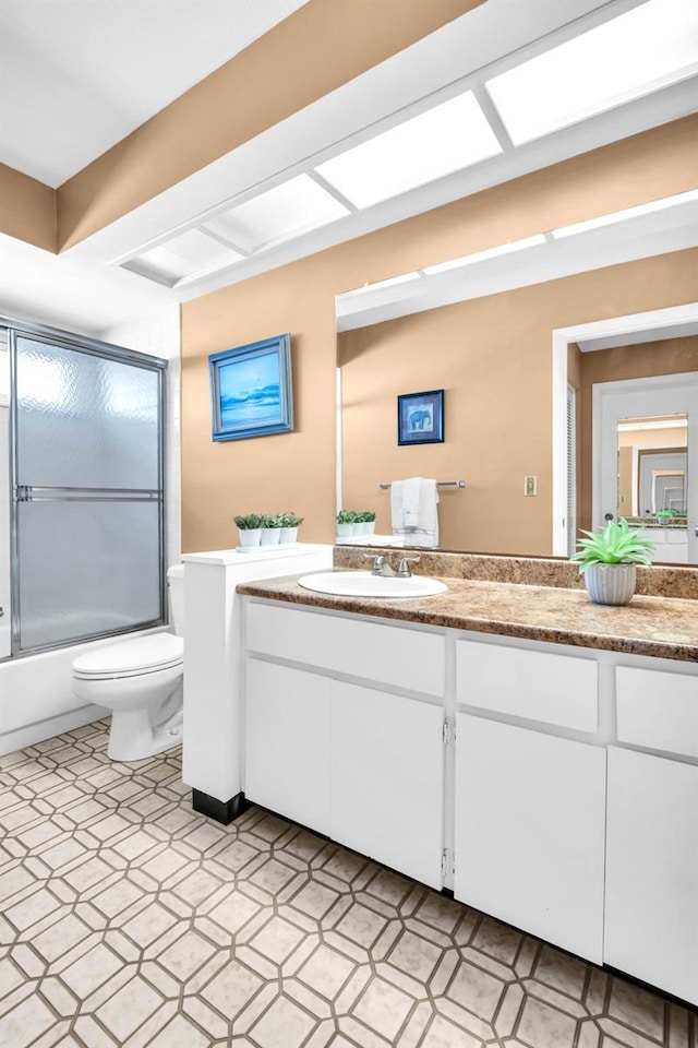 bathroom featuring vanity, tile patterned floors, toilet, and shower / bath combination with glass door