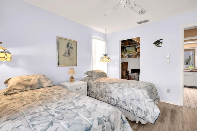 bedroom featuring wood finished floors, visible vents, a closet, and ceiling fan