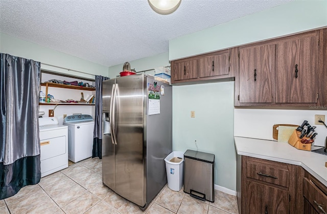 kitchen with a textured ceiling, light tile patterned floors, washing machine and dryer, light countertops, and stainless steel refrigerator with ice dispenser