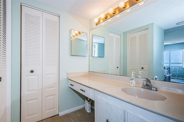 bathroom with a closet, baseboards, a textured ceiling, and vanity