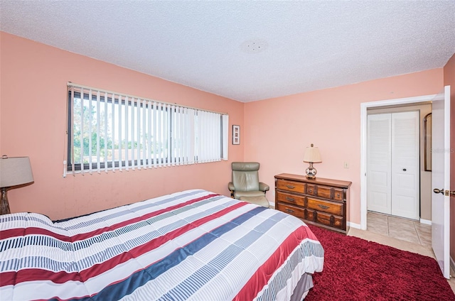 carpeted bedroom featuring tile patterned flooring, a textured ceiling, and baseboards