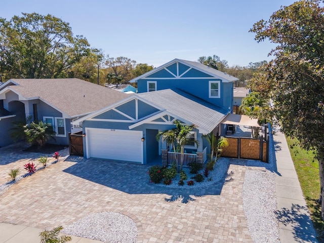 view of front of house with decorative driveway, a garage, fence, and covered porch