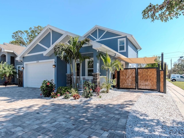 view of front of home featuring a garage, fence, decorative driveway, a gate, and stucco siding