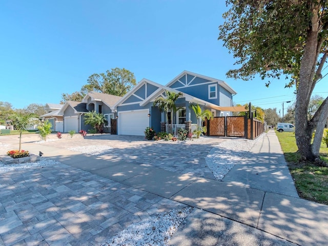 view of front of home featuring driveway, an attached garage, fence, and a gate