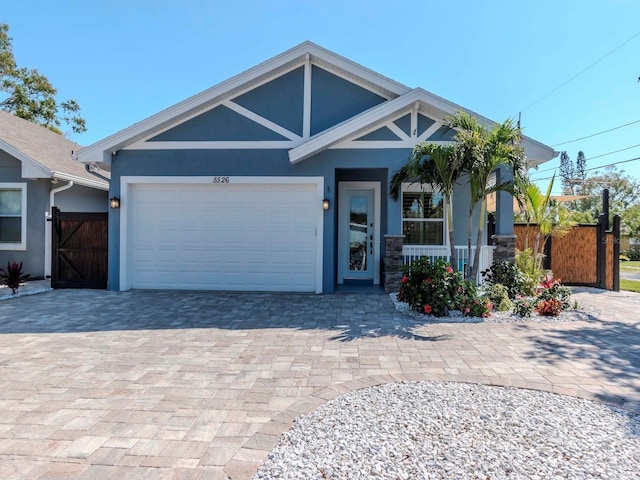 view of front of house featuring decorative driveway, an attached garage, a gate, and stucco siding