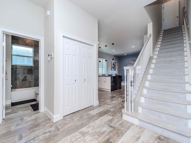 entryway featuring baseboards, a healthy amount of sunlight, stairway, and light wood finished floors