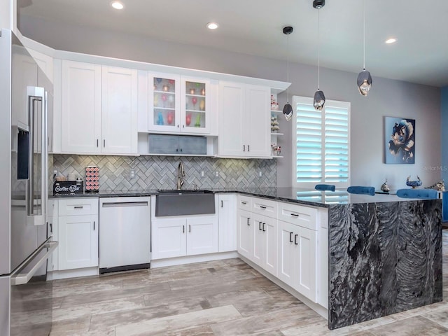 kitchen featuring a peninsula, a sink, appliances with stainless steel finishes, backsplash, and open shelves