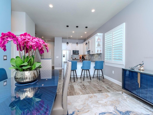 dining space with baseboards, light wood-type flooring, and recessed lighting