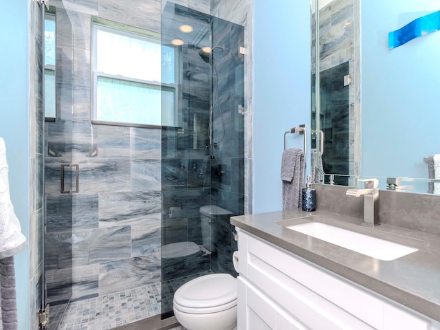 bathroom with a stall shower, vanity, and toilet