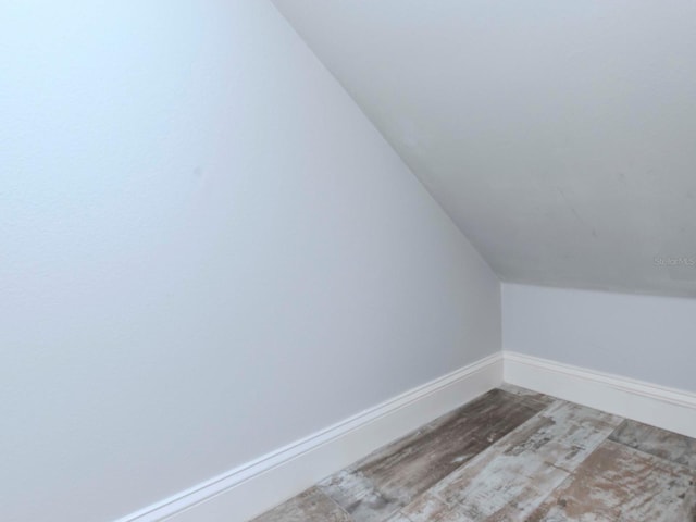 additional living space featuring baseboards, vaulted ceiling, and wood finished floors