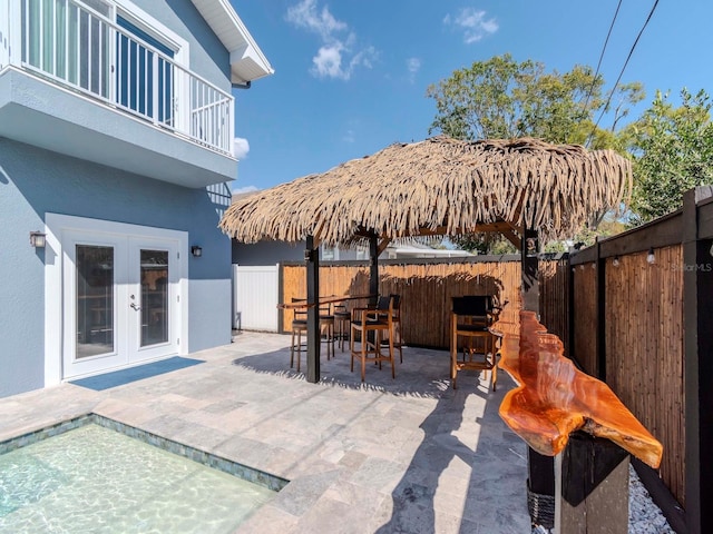 view of patio / terrace with french doors, outdoor dining area, a fenced backyard, and a balcony