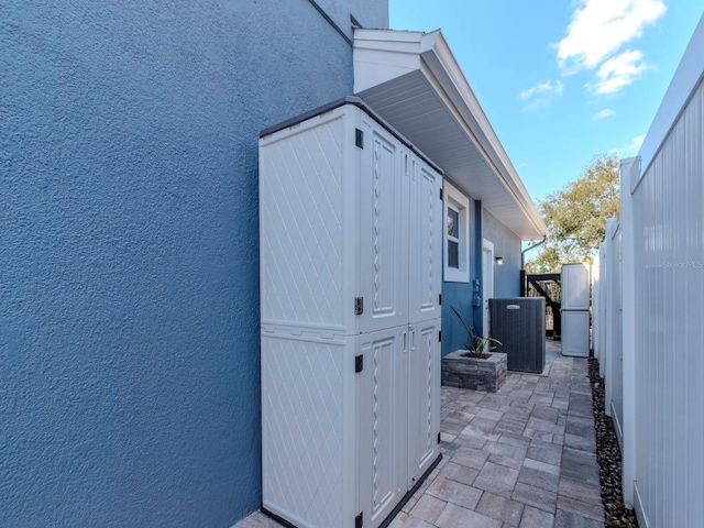 view of home's exterior featuring central air condition unit, fence, an outdoor structure, and stucco siding