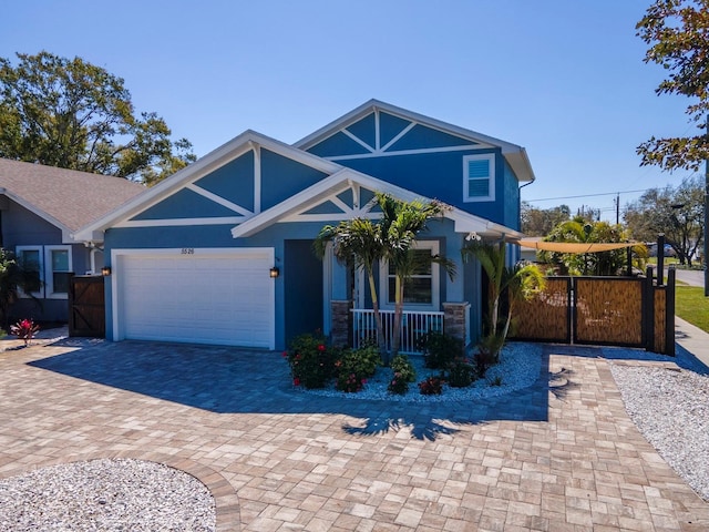 craftsman inspired home featuring a porch, an attached garage, decorative driveway, a gate, and stucco siding