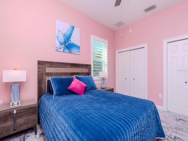 carpeted bedroom featuring visible vents, ceiling fan, and two closets