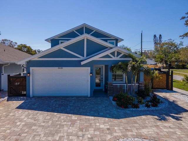5526 14th Ave S, Gulfport, FL 33707 - view of front of home with covered porch, a gate, an attached garage, and stucco siding