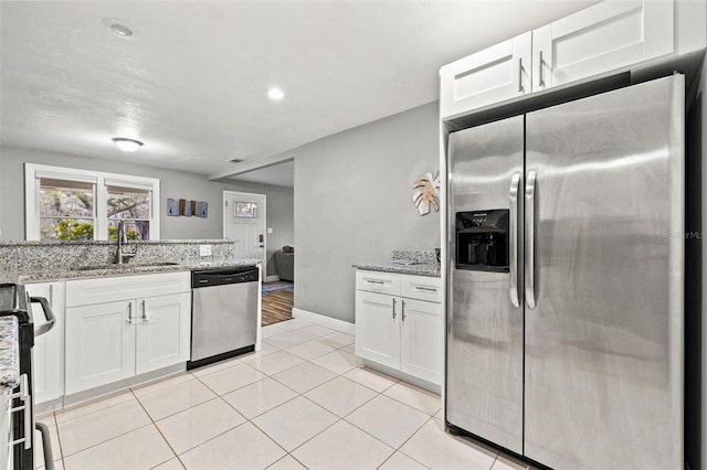 kitchen featuring stainless steel appliances, white cabinets, and light stone countertops