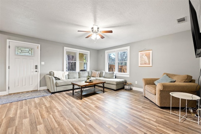 living room with light wood-style flooring, visible vents, and a textured ceiling