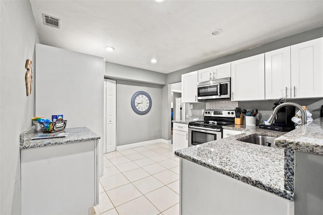 kitchen with stainless steel appliances, white cabinets, visible vents, and light stone counters