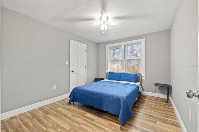 bedroom featuring light wood-type flooring, ceiling fan, baseboards, and a textured ceiling