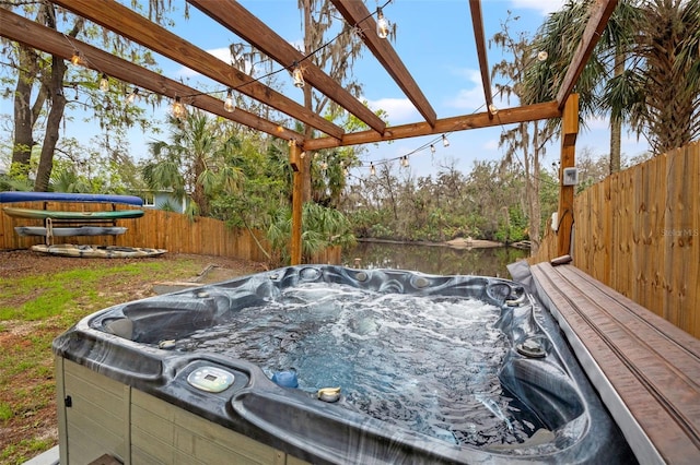 exterior space featuring a water view, fence, a hot tub, and a pergola