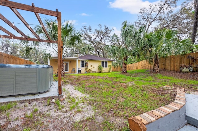 view of yard featuring a fenced backyard, a hot tub, and a pergola