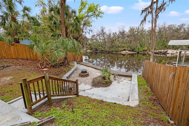 view of yard with a water view, fence, and a dock