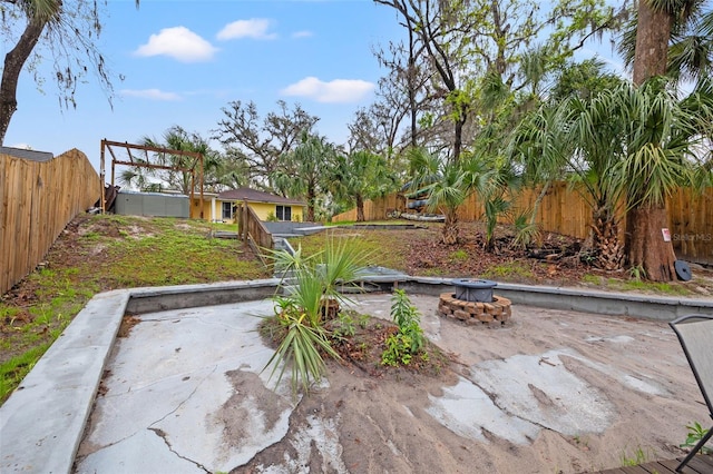 view of yard with an outdoor fire pit, a fenced backyard, and a patio