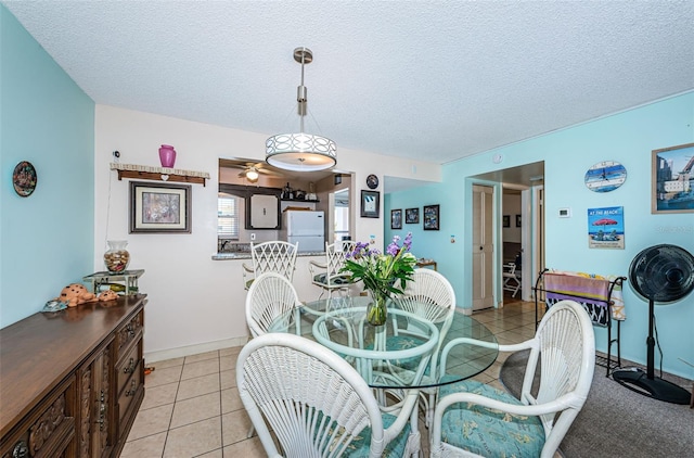 dining room with light tile patterned floors, baseboards, and a textured ceiling