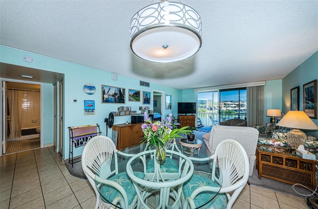 dining area featuring tile patterned flooring, visible vents, and a textured ceiling