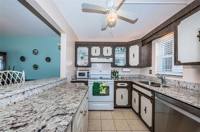 kitchen featuring white appliances, a textured ceiling, under cabinet range hood, a sink, and light tile patterned flooring