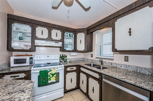 kitchen featuring white appliances, a sink, under cabinet range hood, and a textured ceiling