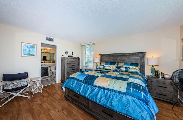 bedroom featuring a textured ceiling, visible vents, and wood finished floors