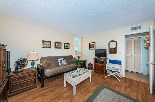 living area with visible vents, a textured ceiling, and wood finished floors