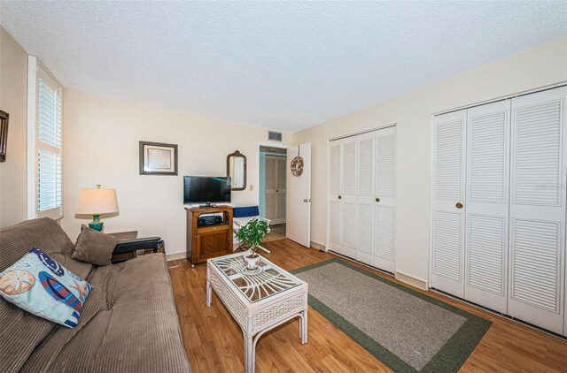 living room featuring visible vents, a textured ceiling, and wood finished floors