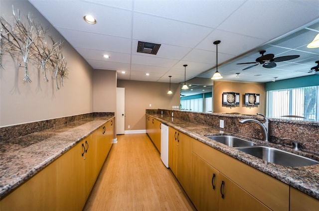 kitchen with decorative light fixtures, light wood finished floors, visible vents, a sink, and white dishwasher