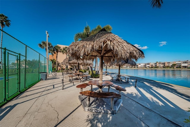 view of property's community featuring a water view, a gate, fence, and a patio