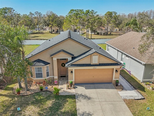 view of front facade featuring driveway, a front yard, a garage, and stucco siding