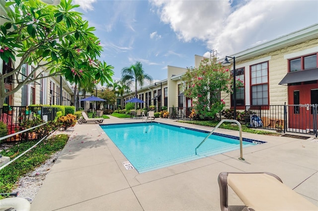 community pool with fence and a patio