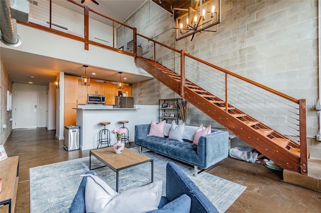 unfurnished living room featuring stairs, a high ceiling, concrete floors, and an inviting chandelier