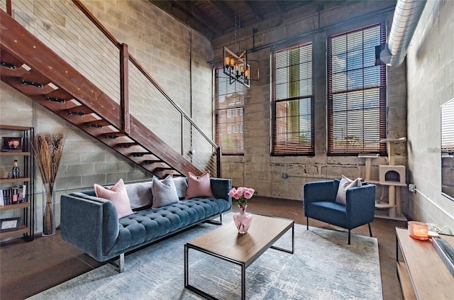 living area with concrete floors, a high ceiling, stairway, and concrete block wall