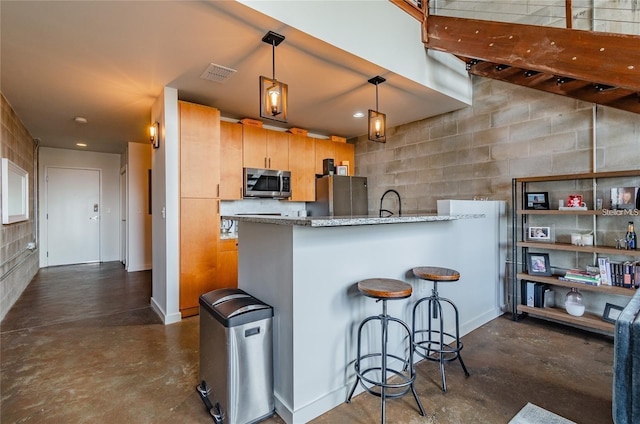 kitchen featuring visible vents, a peninsula, finished concrete floors, stainless steel appliances, and a kitchen bar